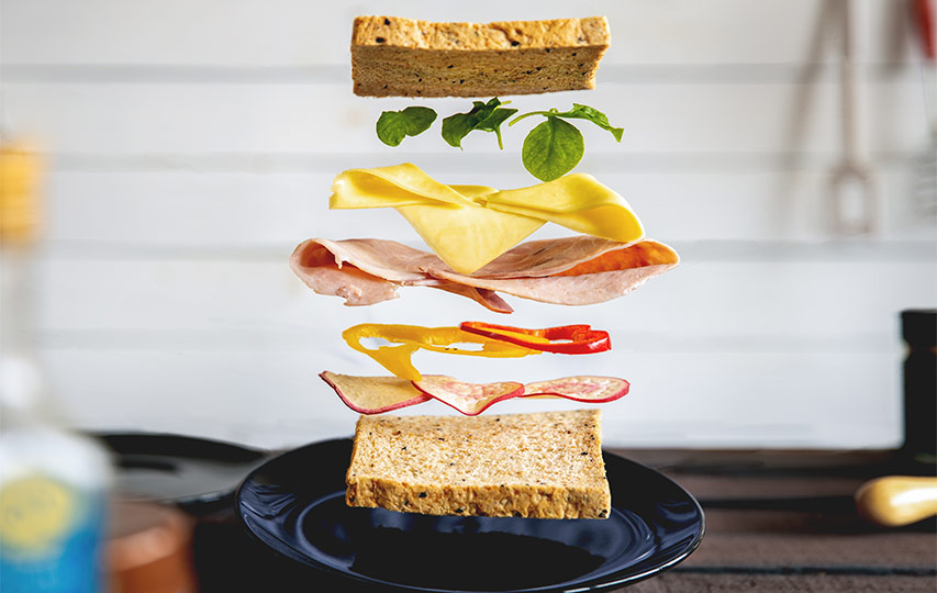 A sandwich with its ingredients above it in the air