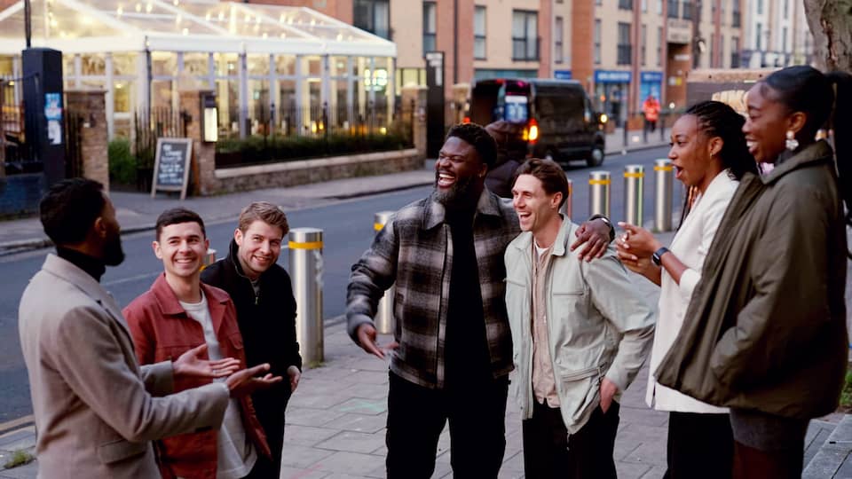 People laughing. They stand at a roadside.