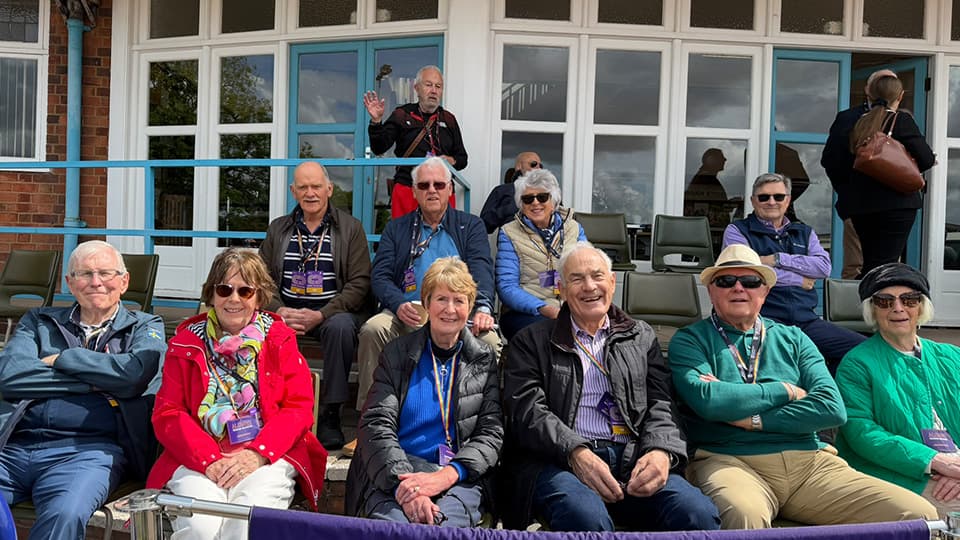 People seated on tiered steps wearing coats, smiling