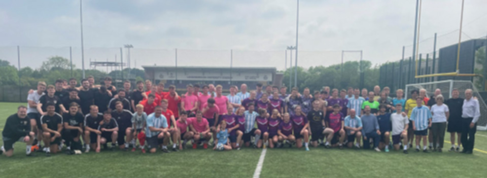 A very large group of football alumni crowded together on a field for a photo