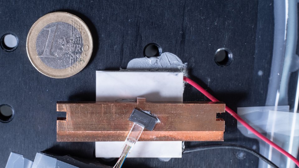 The ‘rainbow on a chip’: a tiny microchip containing a microresonator that produces a precisely organised ‘rainbow’ of light frequencies, known as a microcomb. The chip is the size of a grain of rice, with a one euro coin pictured for scale.