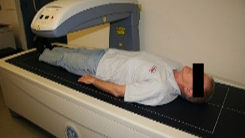 A man lying on a medical bed with a scanner over him