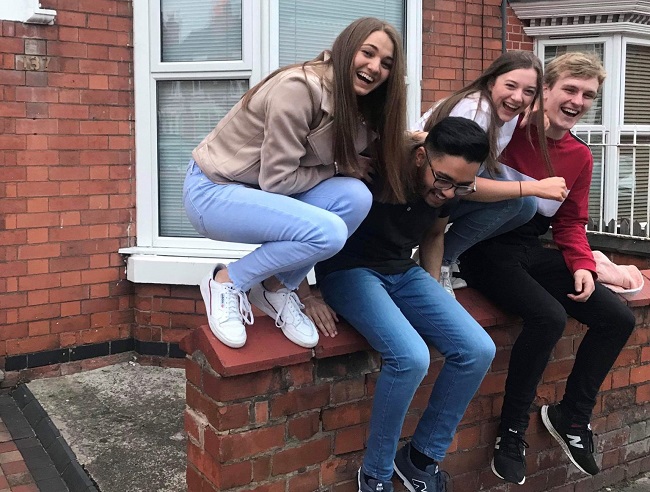 Eleanor and her three house mates sitting on a wall. 