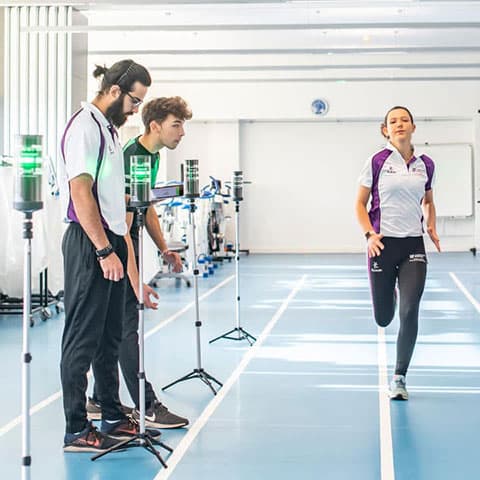 Students conducting tests in the sport, exercise and health sciences labs. A student is running towards the camera through lines of equipment on stands.