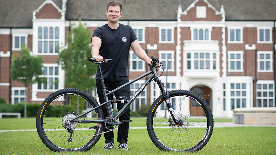 Photo of student Tom Bugler with his first bike design on the Hazlerigg lawn