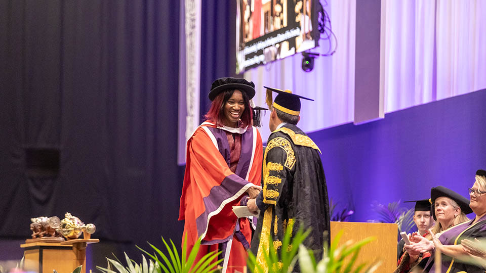 Ama shaking hands with Chancellor Lord Seb Coe on the graduation stage