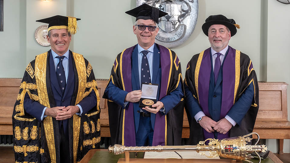 Prof Chris Linton standing between Lord Seb Coe and Professor Nick Jennings in graduation attire