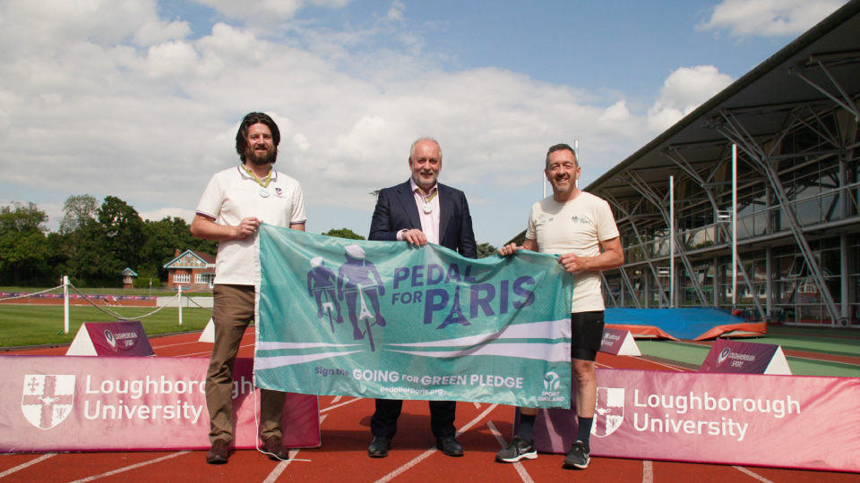 three men hold a flag which states pedal for paris