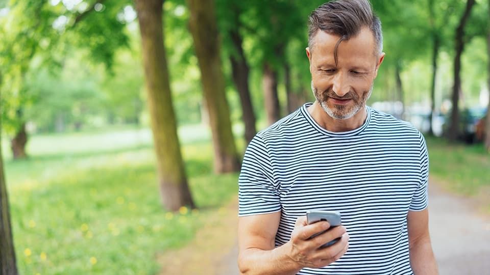 Man looking at phone whilst walking outside