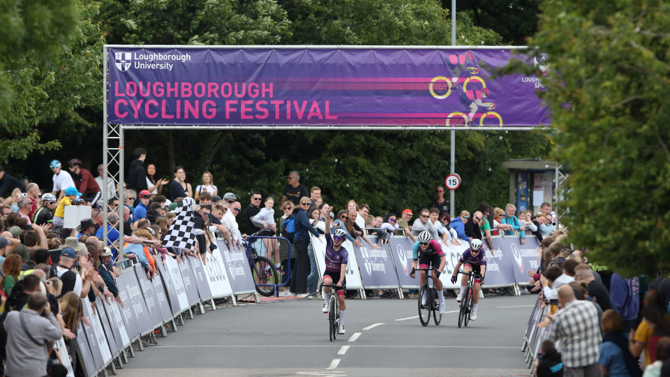 a cyclist crosses the finish line to win a race