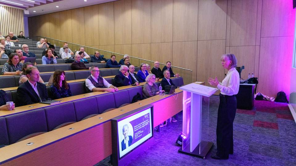 Dame Angela McLean stood presenting to a group of attendees inside a lecture theatre on the campus