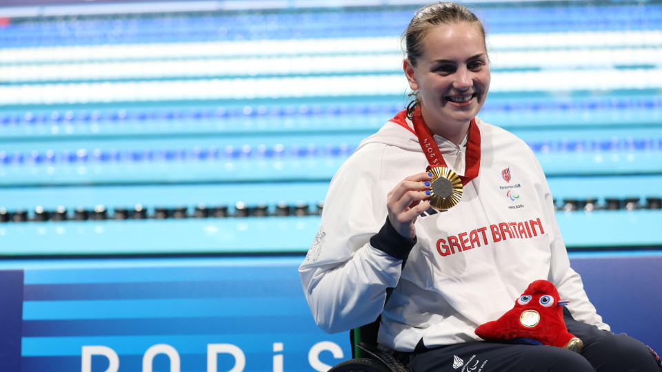 tully kearney, an athlete, poses with a gold paralympic medal