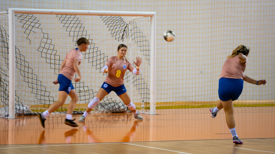 a player hitting a football into a net
