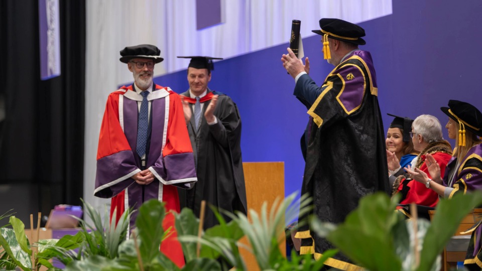 Paul receiving his DUniv honorary degree on stage at Loughborough University's winter graduation ceremony