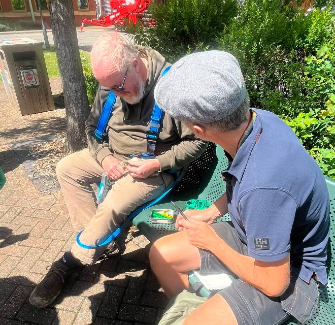 Two people sat on a bench attaching rings to kestrel chicks.