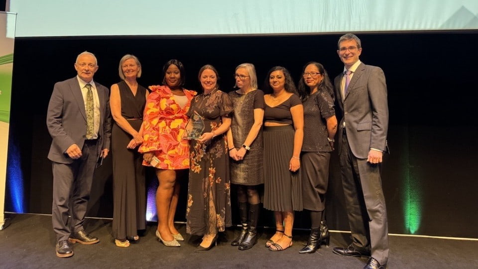 Eight people on a stage collecting and holding an award