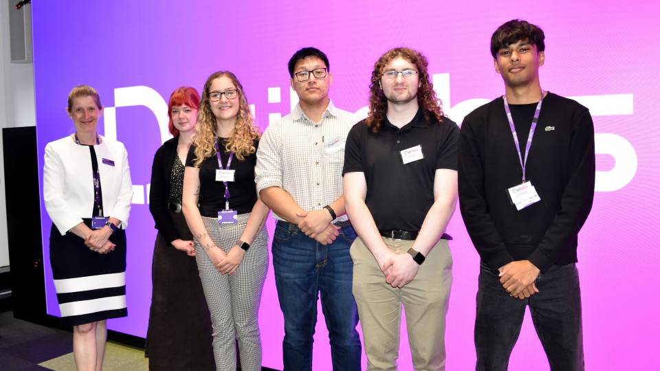 Professor Rachel Thomson and the Summer Interns stood together smiling in front of a large screen